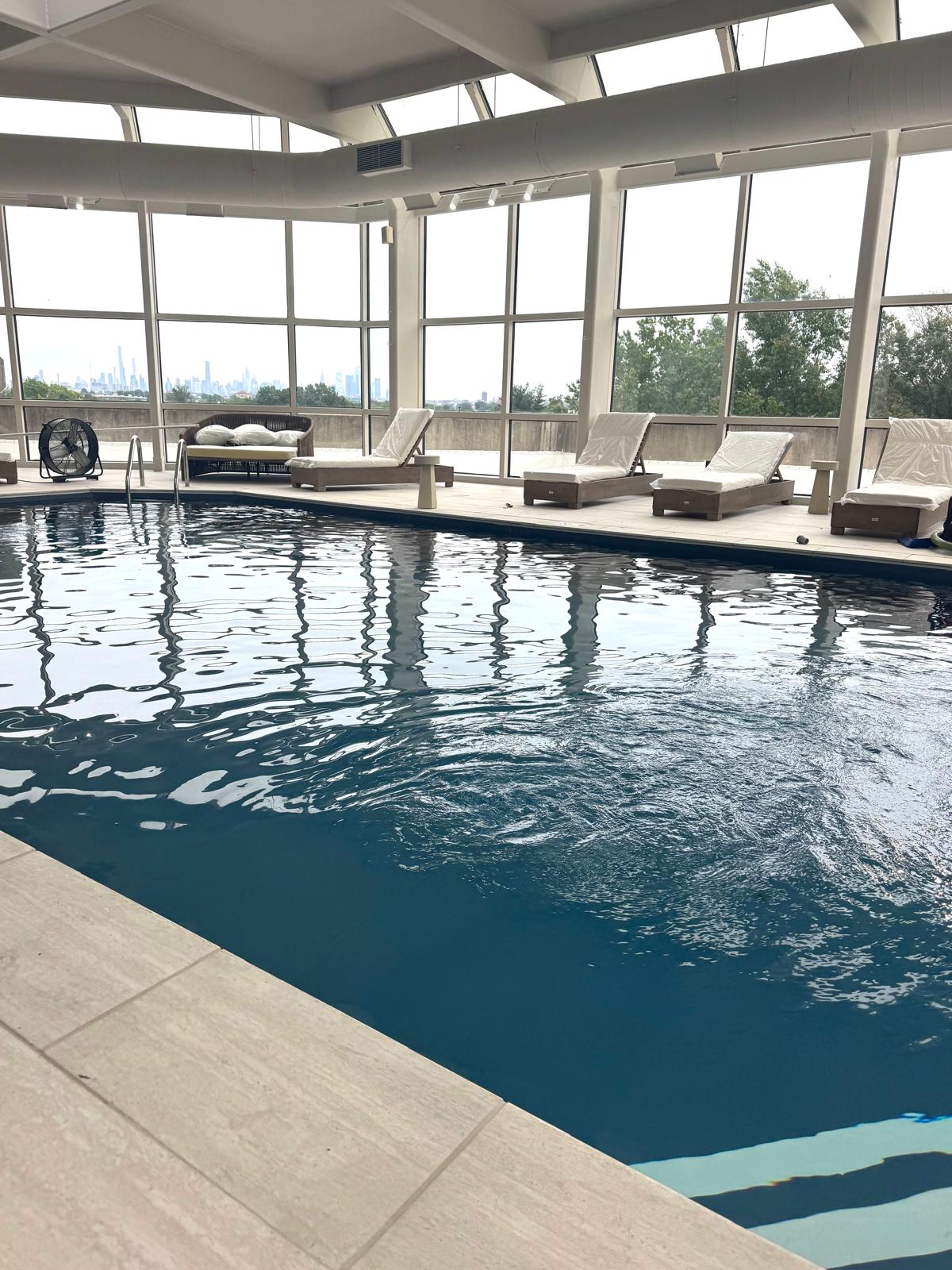 The indoor pool under its skylights with the skyline beyond the glass
