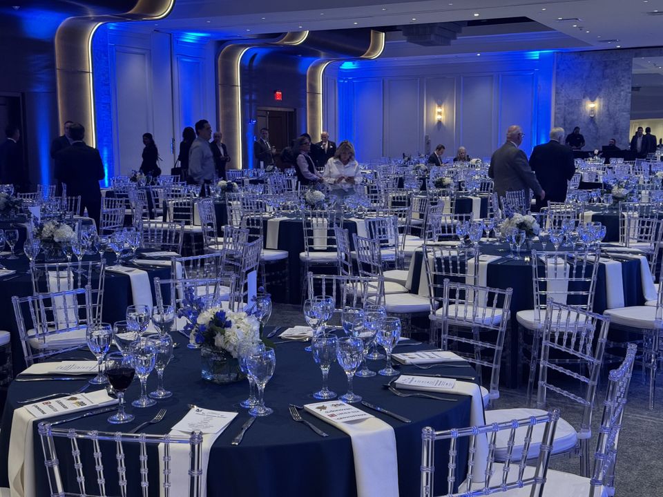 Guests among tables set in navy and white under blue light, in the Horizon Ballroom
