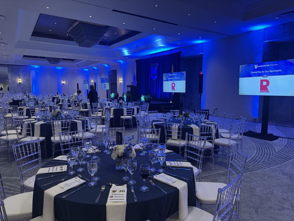 A Meadowlands Chamber dinner in the Horizon Ballroom, a sponsor screen beside a set table