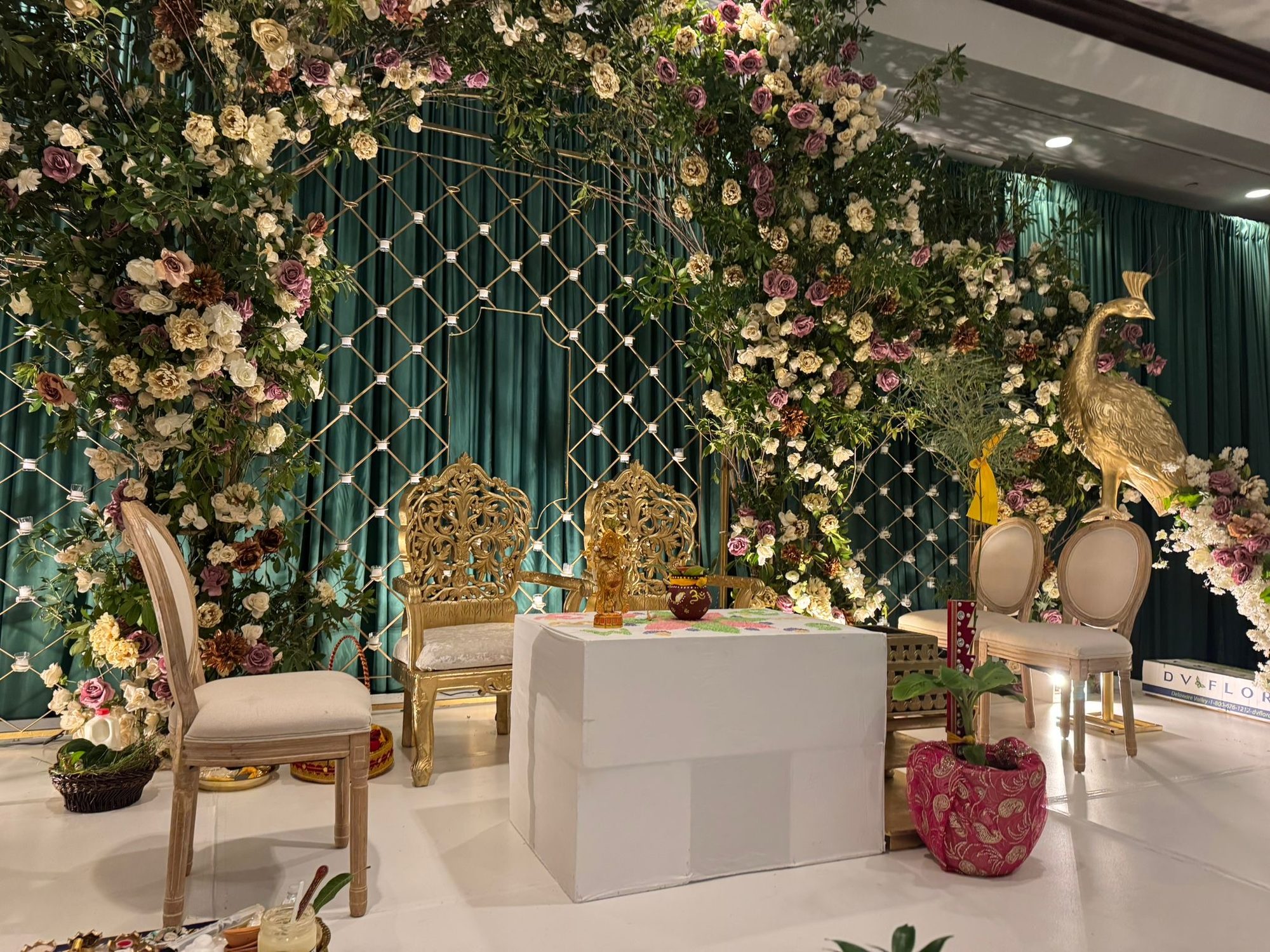 The mandap under its flowers: gold chairs, a gold peacock and the ceremony table