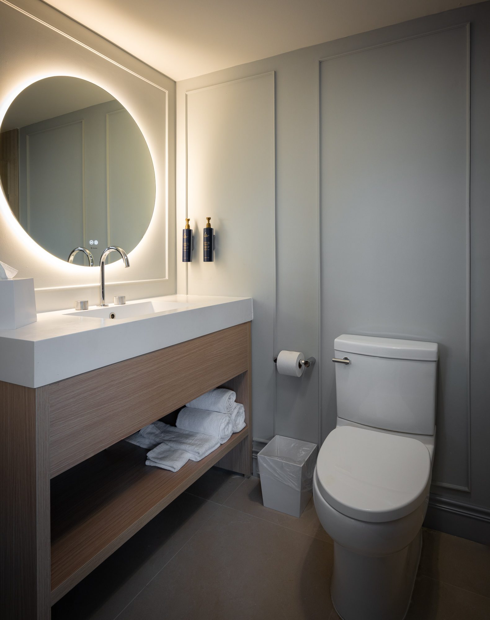 A Luxe bathroom with a round illuminated mirror